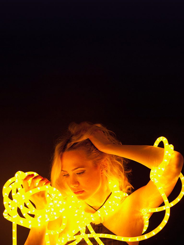 A woman surrounded by yellow glowing fibers