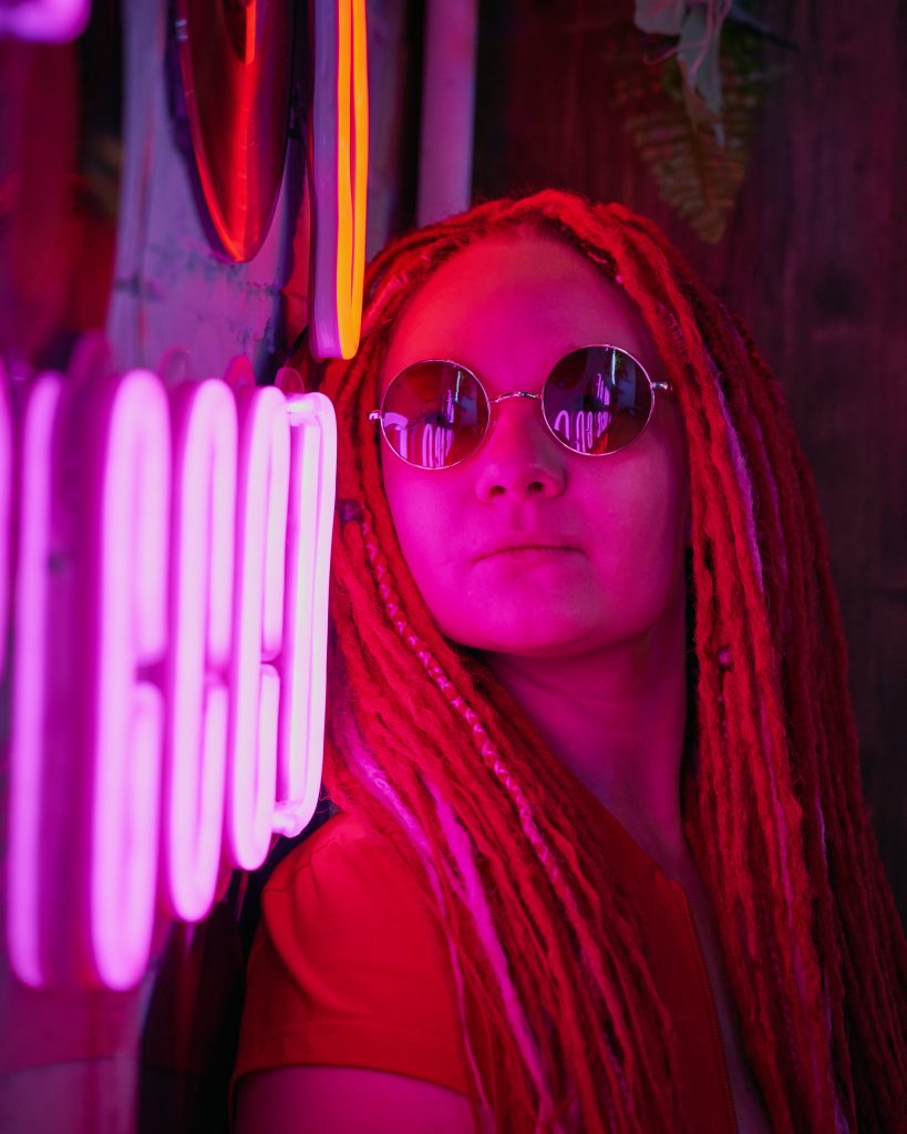Girl with glasses leaning against neon