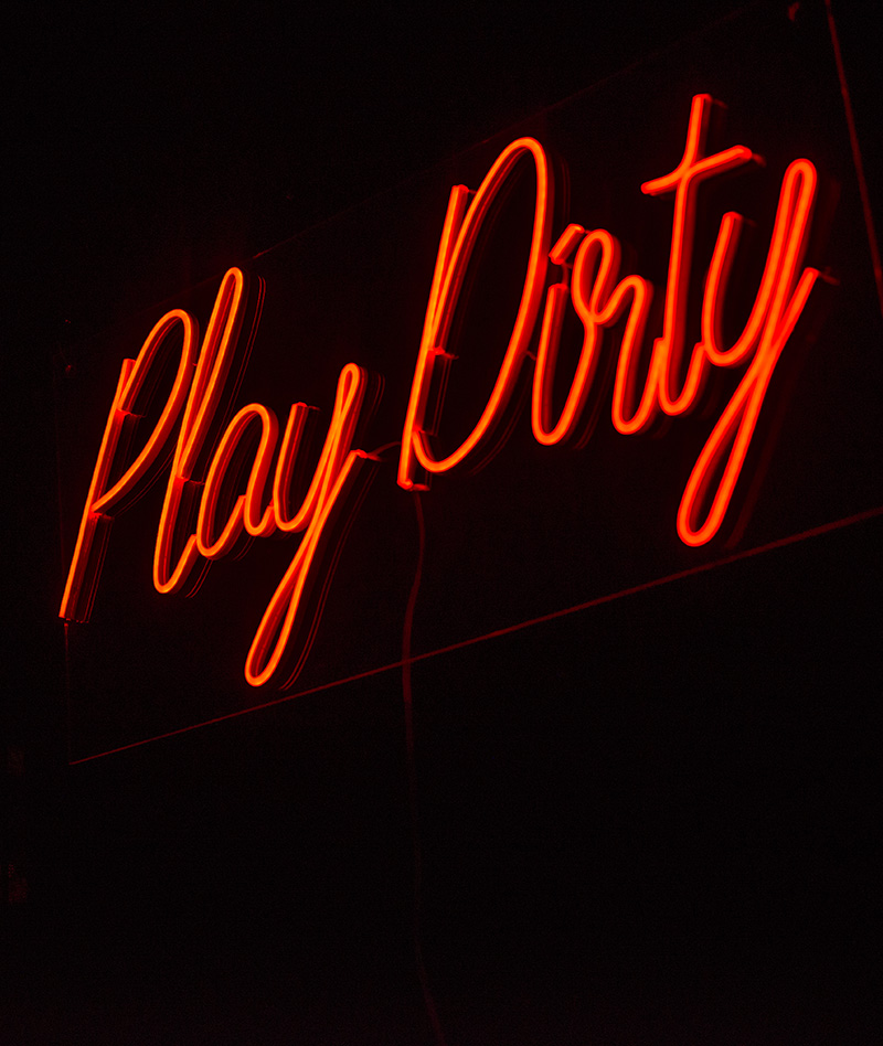 a neon sign that says Play Dirty